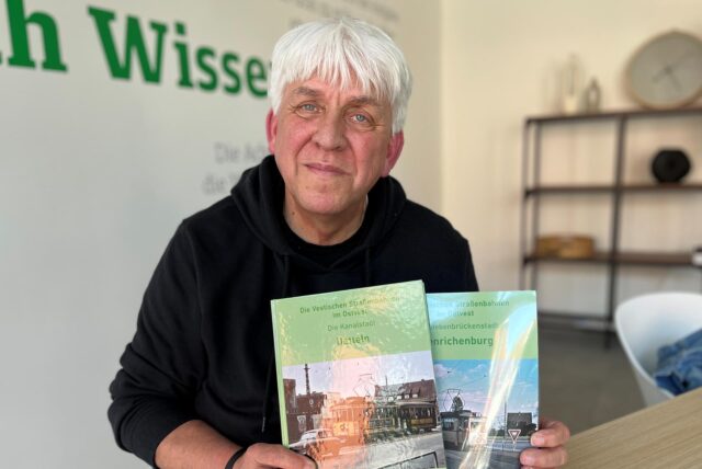 Franz Josef Hauke hält zwei Bücher in der Hand.