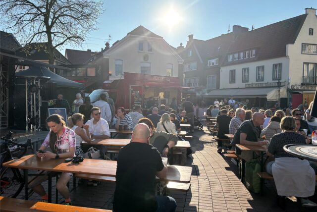 Menschen sitzen am Halterner Marktplatz im Sonnenschein
