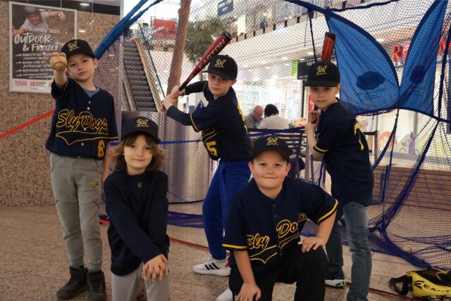 Kinder der Slydogs posieren mit Baseballschlägern für die Kamera.