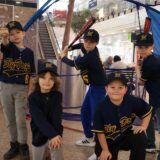 Kinder der Slydogs posieren mit Baseballschlägern für die Kamera.