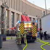 Ein Löschfahrzeug der Feuerwehr steht vor dem Palais Vest in Recklinghausen. Gelbe Schläuche liegen auf dem Boden. Neben Passanten sind auch zwei Feuerwehrleute in Montur zu sehen.