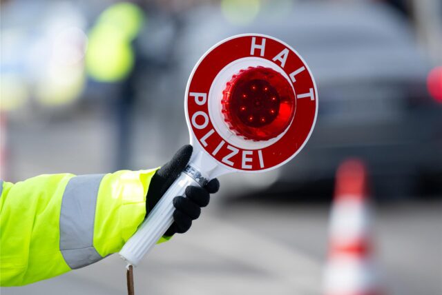 Eine Hand hält eine Polizeikelle hoch.