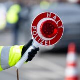 Eine Hand hält eine Polizeikelle hoch.