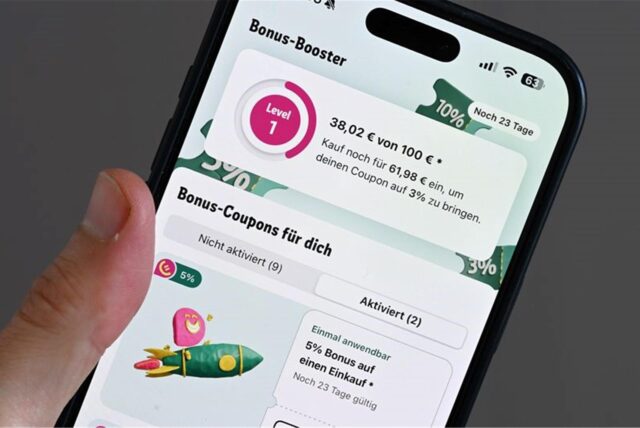 Ein Mann hält sein Smartphone, auf dem die Rewe-App mit Rabatten zu sehen ist (gestellte Szene).