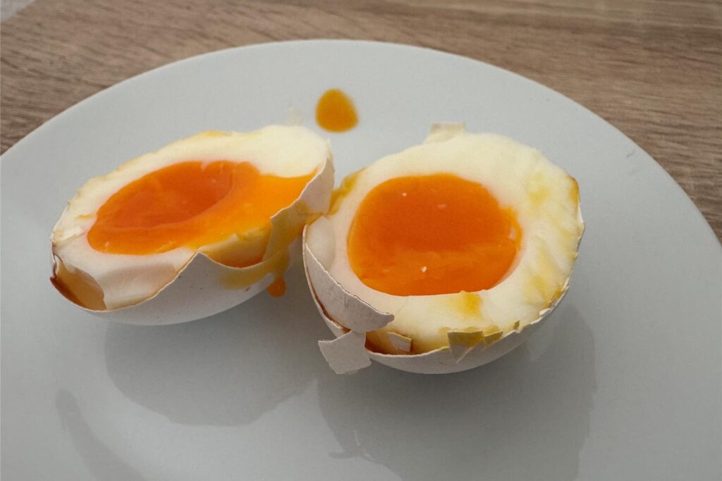 Ein in zwei Hälften geteiltes, wachsweich gekochtes Ei, das im Airfryer gegart wurde. Ein in zwei Hälften geteiltes, wachsweich gekochtes Ei, das im Airfryer gegart wurde.