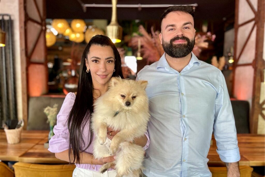 Die Betreiber Mehmet und Derya stehen mit einem Hund im Gastraum des Wamo in Dortmund.