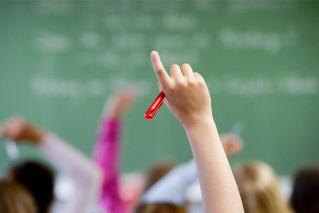 Schüler zeigen im Unterricht auf.