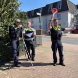 Drei Polizisten stehen an einer Laserpistole und kontrollieren den Verkehr