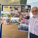 Dieter Böhmer (84) vor einer Tafel mit alten Fotos und Zeitungsartikeln.