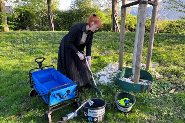 Christina Ahlers ist bei der Mission Clean (it) up Ruhrgebiet und hebt in Herten-Süd mit einer Greifzange Müll auf.