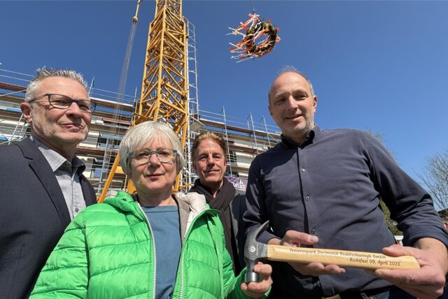 Axel Kunstmann, Barbara Brunsing, Andreas Anspach und Uwe Poganiatz-Heine unter dem Richtkranz vor dem Baukran auf der Baustelle an der Bodelschwingher Straße.