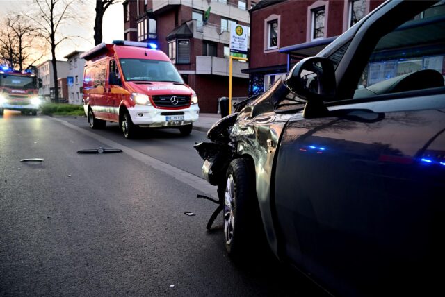 Ein kaputtes Auto steht vor zwei Feuerwehrwagen.