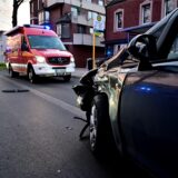 Ein kaputtes Auto steht vor zwei Feuerwehrwagen.