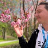 Ruhr Nachichten-Reporter Tim Hübbertz hält im Rombergpark in Dortmund einen Zweig mit Kirschblüten in der Hand.