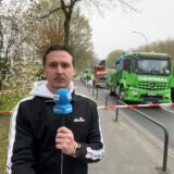Reporter Tim Hübbertz von den Ruhr Nachrichten steht mit einem Mikrofon vor der Kamera. Im Hintergrund sind mehrere Arbeitsfahrzeuge zu sehen, darunter ein grüner LKW der Firma Wiemers.