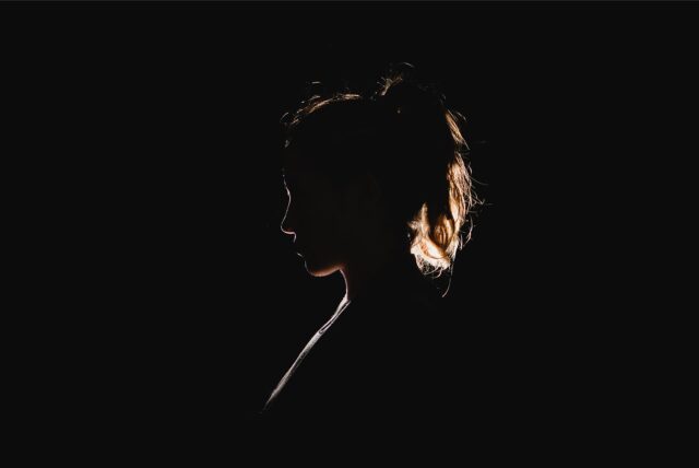 Silhouette einer Frau vor schwarzem Hintergrund.