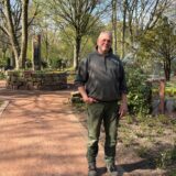 Gärtnermeister Andreas Gehron steht auf dem Hauptfriedhof in Marl. Im Hintergrund sind Anpflanzungen und Gräber und eine laufende Sprinkleranlage zu sehen.