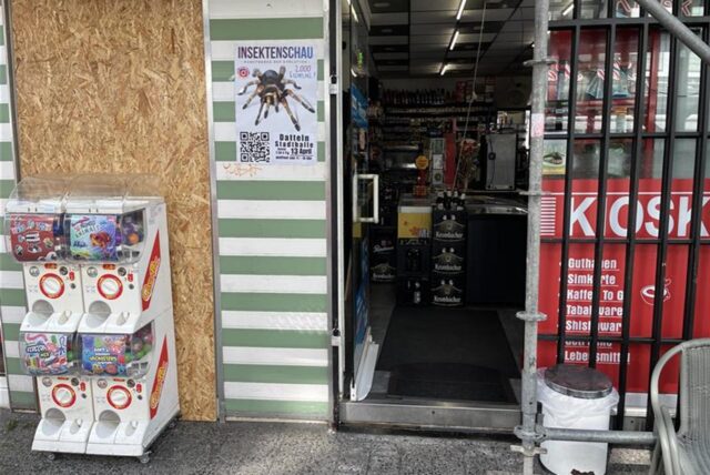 Ein Kiosk in Datteln. Die linke Fensterscheibe, die Diebe mit einem Gullydeckel eingeschlagen haben, wird durch eine Holzplatte verdeckt.