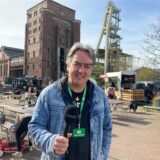Redakteur Patrick Köllner mit einem Mikrofon in der Hand. Er berichtet vom ersten Feierabendmarkt auf dem Gelände der Zeche Ewald in Herten-Süd.