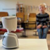 Der AV1-Avatar steht in einem Klassenzimmer der Lindenschule in Castrop-Rauxel.