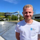 Leon Neumeister von der Bädergesellschaft Waltrop steht vor dem Nichtschwimmerbecken des Freibads. Im Hintergrund ist zudem die große Wasserrutsche erkennbar.