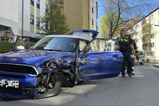 Ein blauer Mini nach steht nach einem Unfall auf der Straße.
