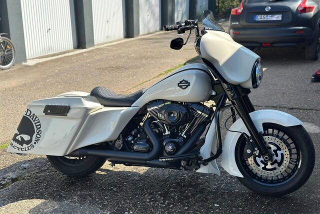 Die weiße Harley auf einem Parkplatz.