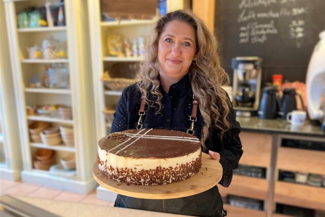 Aida Suvalic in ihrem Café Kulisse in Herten-Scherlebeck hinter der Theke und hält eine selbstgebackene Torte in den Händen.