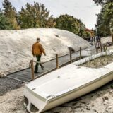 Das Bild zeigt eine zusammengesetzte Aufnahme. Auf der linken Seite ist ein Dr. Patrick Knopf mit Brille und hellem Kapuzenpullover zu sehen, während die rechte Seite einen Sandweg mit Vegetation und Dünen zeigt.