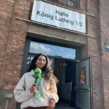 RZ-Reporterin Rosi Taslima Azam steht mit grünem Mikrofon vor der Halle König Ludwig in Recklinghausen.