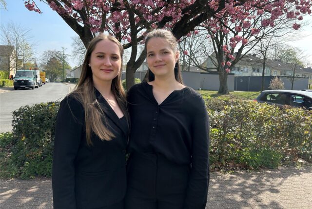 Emily und Katharina stehen vor einem Kirschbaum.