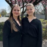 Emily und Katharina stehen vor einem Kirschbaum.