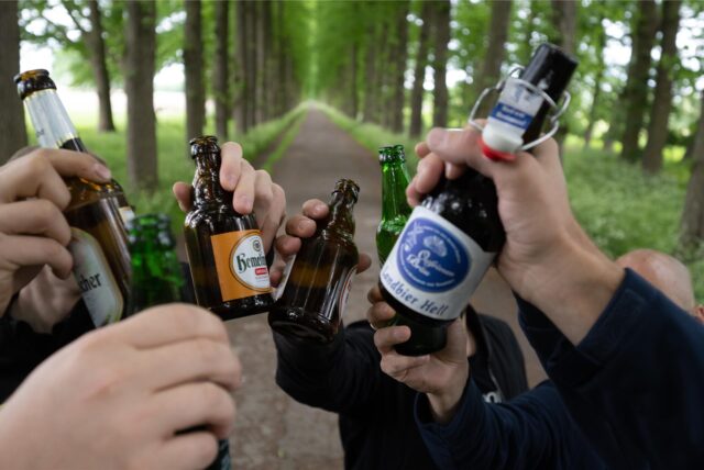 Sechs Männer stoßen mit verschiedenen Bierflaschen an.