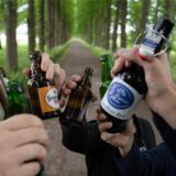 Sechs Männer stoßen mit verschiedenen Bierflaschen an.