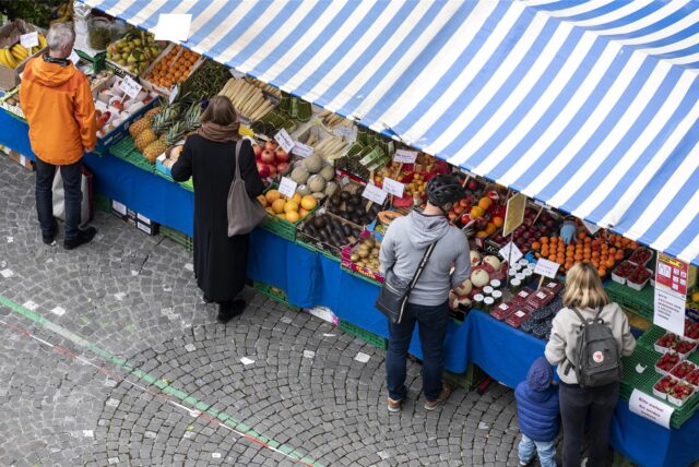 Menschen kaufen an Wochenmarktständen Obst und Gemüse ein (Symbolbild).