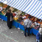 Menschen kaufen an Wochenmarktständen Obst und Gemüse ein (Symbolbild).