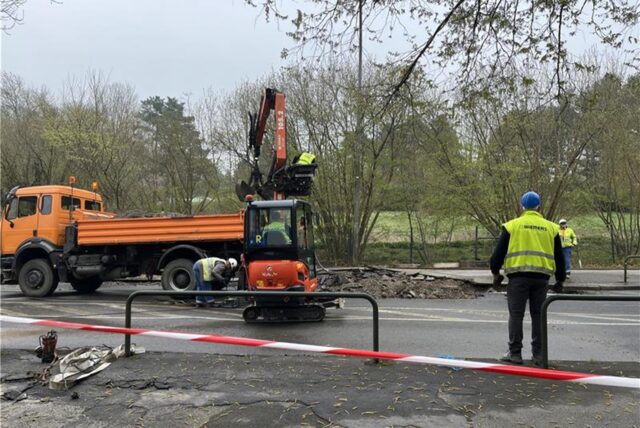Auf einer Baustelle wird der Boden aufgerissen. Im Hintergrund sind mehrere Arbeitsfahrzeuge.