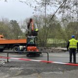 Auf einer Baustelle wird der Boden aufgerissen. Im Hintergrund sind mehrere Arbeitsfahrzeuge.