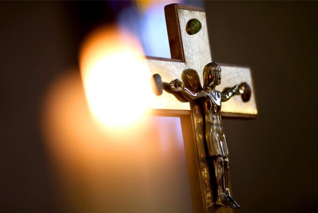 Ein Jesuskreuz und eine brennende Kerze