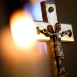 Ein Jesuskreuz und eine brennende Kerze