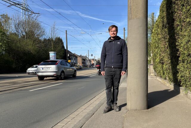 Marius Kerkering steht auf dem Bürgersteig des Brackeler Hellweg neben einem Oberleitungsmast. Auf der Straße fahren Autos.