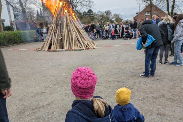 Zwei Kinder stehen vor einem Osterfeuer.