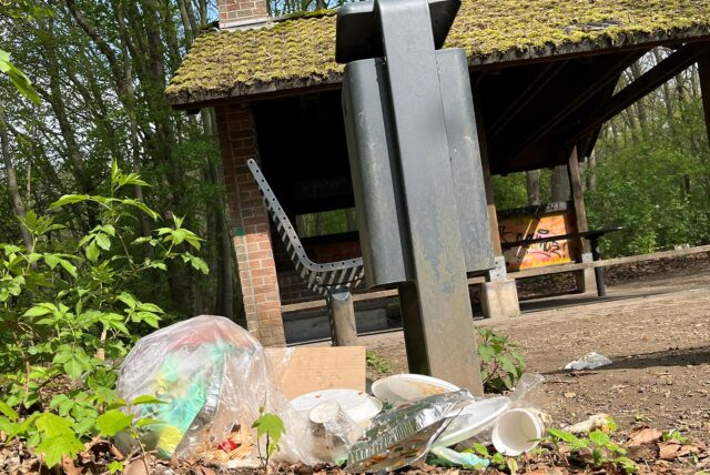 Plastikmüll liegt auf dem Boden vor einem Mülleimer.