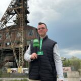 Eine Person mit schwarzer Weste steht auf einem ehemaligen Zechengelände.