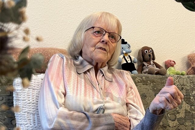 Eine hochbetagte Frau sitzt auf einem Sofa