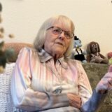 Eine hochbetagte Frau sitzt auf einem Sofa