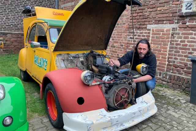 Björn Faasen kniet neben seinem Citroen 2CV und schraubt im Motorraum.