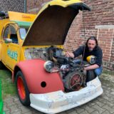 Björn Faasen kniet neben seinem Citroen 2CV und schraubt im Motorraum.