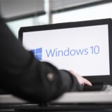 Eine Person tippt an einem Laptop, auf dessen Bildschirm das Microsoft Windows 10 Logo zu sehen ist.