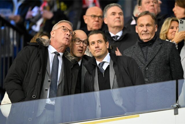 Thomas Treß spricht auf der Tribüne mit Carsten Cramer und Lars Ricken. Im Hintergrund steht Hans-Joachim Watzke.